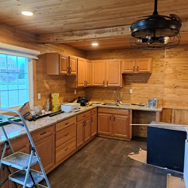 Rustic-style kitchen levelling renovation with wood-paneled ceiling, new cabinets, and granite countertops in progress