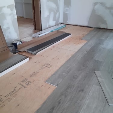 Luxury vinyl plank flooring installation over levelled plywood subfloor during residential renovation