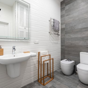 Baño con ducha de obra, mampara de cristal y revestimiento cerámico gris oscuro.