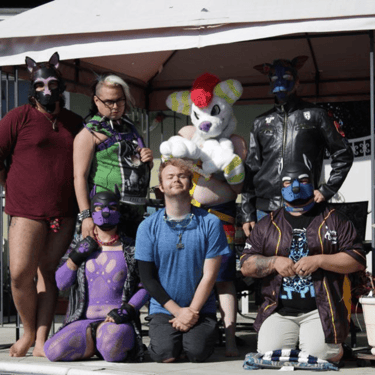 Group photo of people in pup and furry masks and costumes.