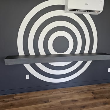 Game room with a black feature wall showcasing a striking bullseye design and a functional floating shelf for added style