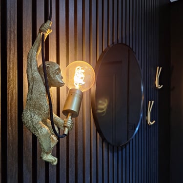 Un luminaire singe sur des panneaux en latte de bois