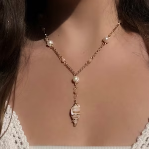 A gold necklace with pearls and a simple shell pendant.