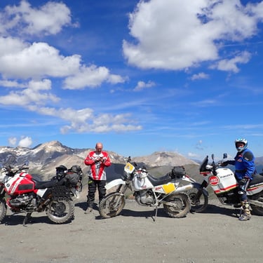 a group of motorcyclists standing in front of a mountain