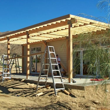 Large wood structure being framed in desert area.