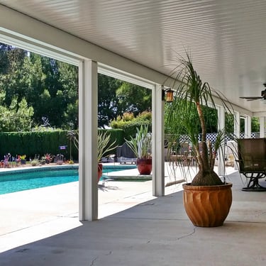 Potted plants under covered patio next to pool.
