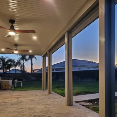 Patio cover at night with palm trees.