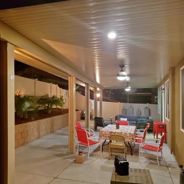 Red chairs and table under Alumaood cover at night.