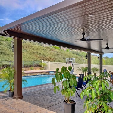 Large brown ptio roof next to pool and hillside.