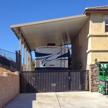 Motorhome under Alumawood carport with a man lift next to it.