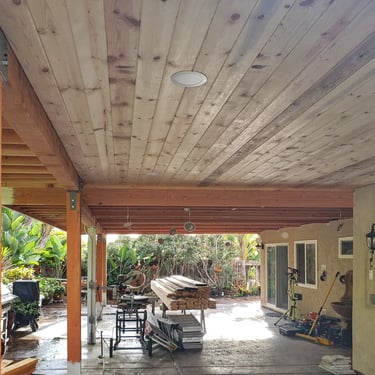 Wood roof structure with beams and T & G ceiling being installed.