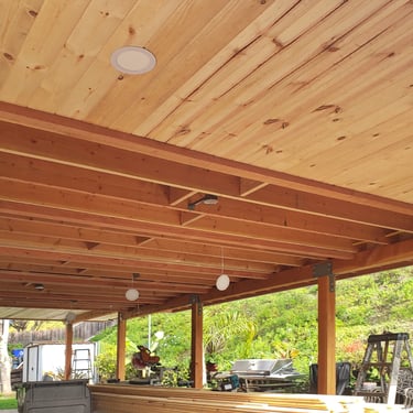 Wood roof structure with beams and T & G ceiling being installed.