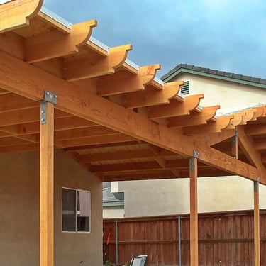 Small wood patio cover with gabled roof and corbel rafter tails.