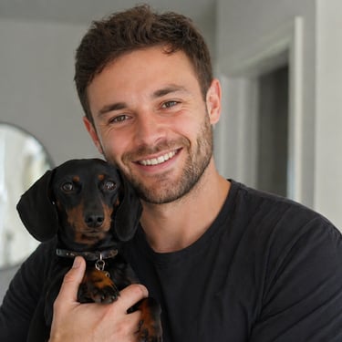 Smiling man holding a small black dachshund indoors in a bright home setting