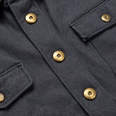 Close-up of durable canvas work jacket stitching, heavy-duty brass buttons, industrial workshop feel