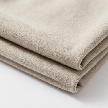 Tactile view of heavy fleece jogging fabric texture, neatly folded, neutral tones, soft studio shadows