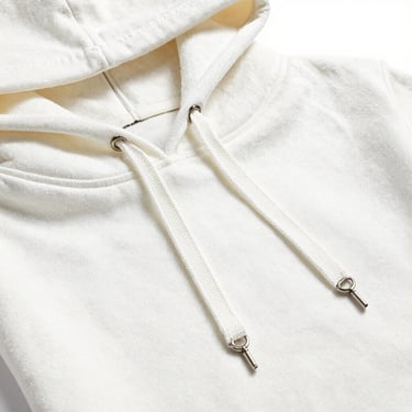Close-up of a neatly folded premium cotton hoodie, focus on thick drawstrings and metal eyelets, clean studio lighting