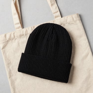 Overhead flat-lay of a premium knit beanie and a heavy canvas tote bag, minimalist composition, clean light