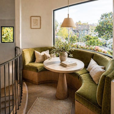 ustom curved banquette seating by a large window with round table and soft natural light