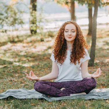 ragazza con capelli rossi in posa yoga seduta con gli occhi chiusi