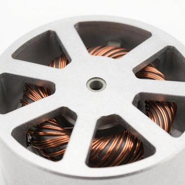 Macro close-up of an electric fan motor showing copper winding, clean metallic textures, bright studio lighting, 50mm