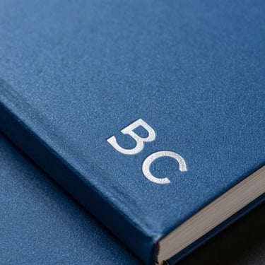 Macro shot of physical brand book binding, heavy slate blue cover, minimalist typography.