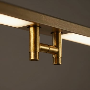 Macro shot of matte brass joints on a minimalist light fixture, soft warm glow, clean lines.