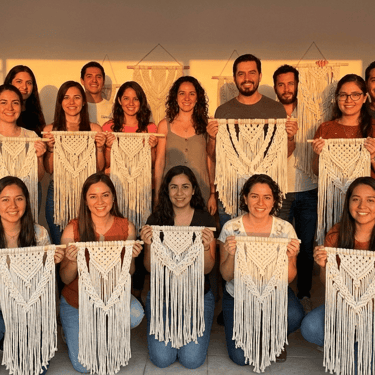 Personas mostrando las piezas que hicieron en un taller de macramé.