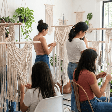Mujeres trabajando piezas de macramé en un taller.