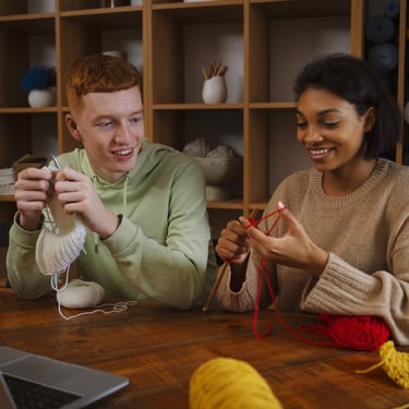 dos personas sonrientes aprendiendo a tejer con agujas