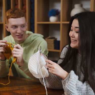 dos personas tejiendo con agujas en un taller
