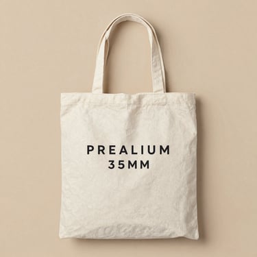 Minimalist flat lay of a premium custom canvas tote bag with clean screen-printed typography, soft natural daylight, warm sand tone background, 35mm