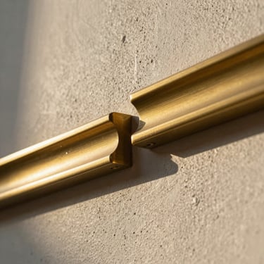Macro close-up of premium textured plaster and brushed brass architectural details, low-angle golden hour lighting casting dramatic shadows