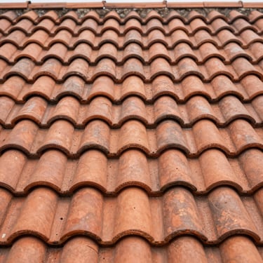 Close-up of interlocking terracotta roof tiles, warm clay tones, weathered texture