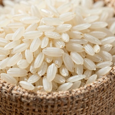 Macro close-up of polished white Basmati rice grains held in a coarse jute sack under harsh natural sunlight.