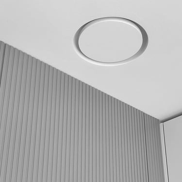 ERGOVENT RONDO 160 flush-installed in white ceiling showing seamless round concealed diffuser above slatted wall paneling