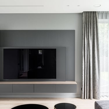 Modern living room TV wall with ERGOVENT RONDO invisible diffuser flush-mounted in white ceiling, gray fluted wall panel.