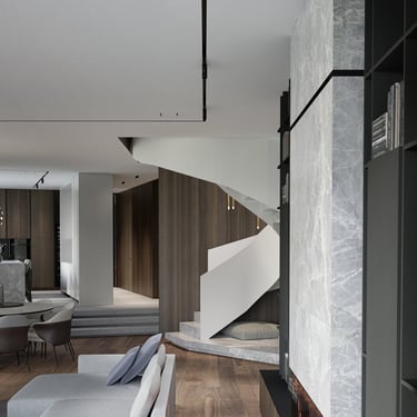 Luxury interior with ERGOVENT KVADRO diffuser in ceiling, marble fireplace wall and sculptural spiral staircase.