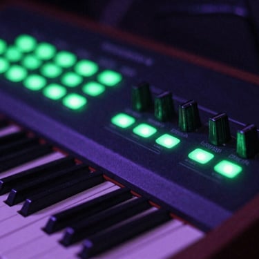 Close-up of a vintage analog synthesizer with glowing green LEDs in a dark studio room, high contrast, gritty