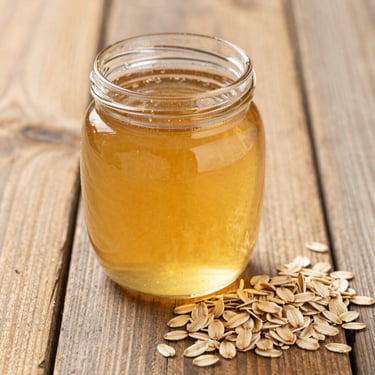 A glass jar of pure golden honey sitting next to organic rolled oats on a sunlit rustic wooden table