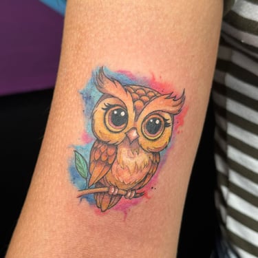 Small owl tattoo on the arm of a woman. 