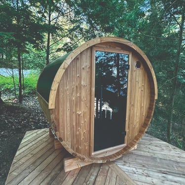 Scandinavian barrel sauna with panoramic glass window positioned in wooded Ontario landscape