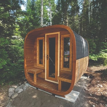 Outdoor barrel sauna with glass door installed in forest setting designed for Ontario weather