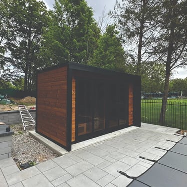 Custom outdoor cedar sauna with flat roof installed on concrete pad in Ontario backyard
