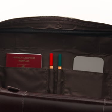 Geantă de voiaj din piele maro închis, fotografiată în interior, pe fundal alb.