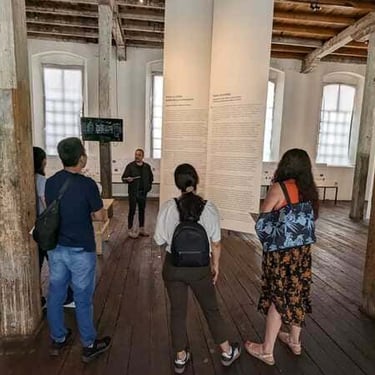 Alumnos aprendiendo sobre la historia de un lugar, en un museo, mientras escuchen a el maestro hablar en inglés.