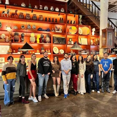 Grupo de alumnos posando en un fondo con piezas de cerámica.