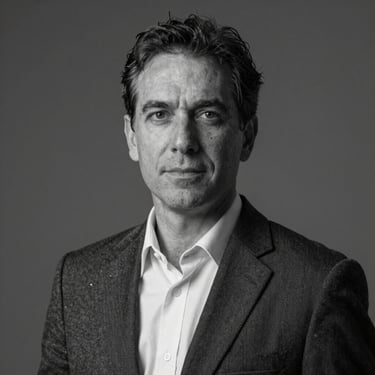 Retrato corporativo em preto e branco de um homem de meia-idade com óculos de armação fina, terno sóbrio, iluminação lateral focada
