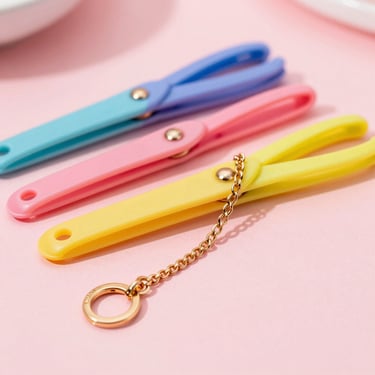 Colección de pinzas para el cabello coloridas y collares dorados finos sobre una superficie rosa pastel