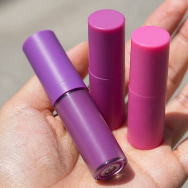 Muestras de labiales líquidos de tonos magentas y rosas sobre piel cálida con luz natural brillante